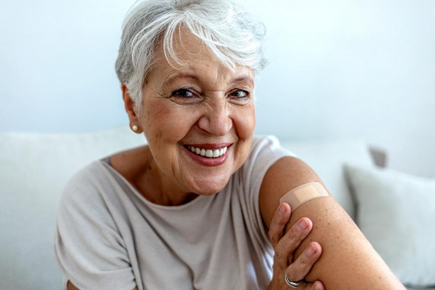 Happy healthy senior woman with bandaid on arm after flu shot