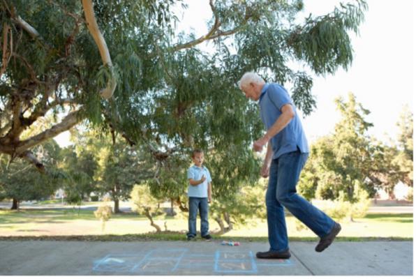 A senior man playing hopscotch with his grandson