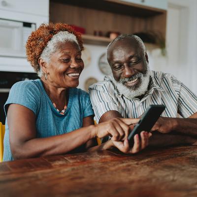 A senior couple looking at the same smart phone and smiling