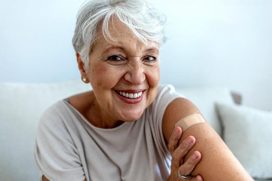 Happy healthy senior woman with bandaid on arm after flu shot